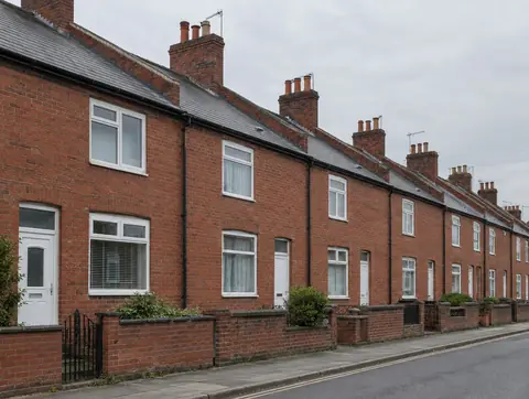 Row of red brick terraced houses with party walls rising through the roofline